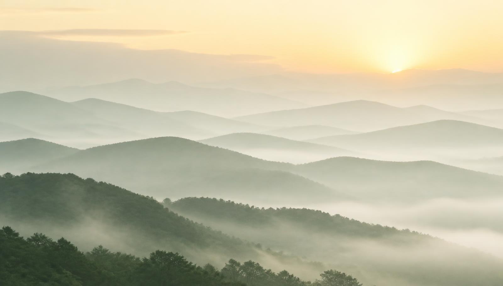 Montanhas em camadas de névoa ao amanhecer